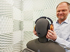 Mitarbeiter legt Kopfhörer auf Kunstkopf, Dienstleistungs- und Produkttest