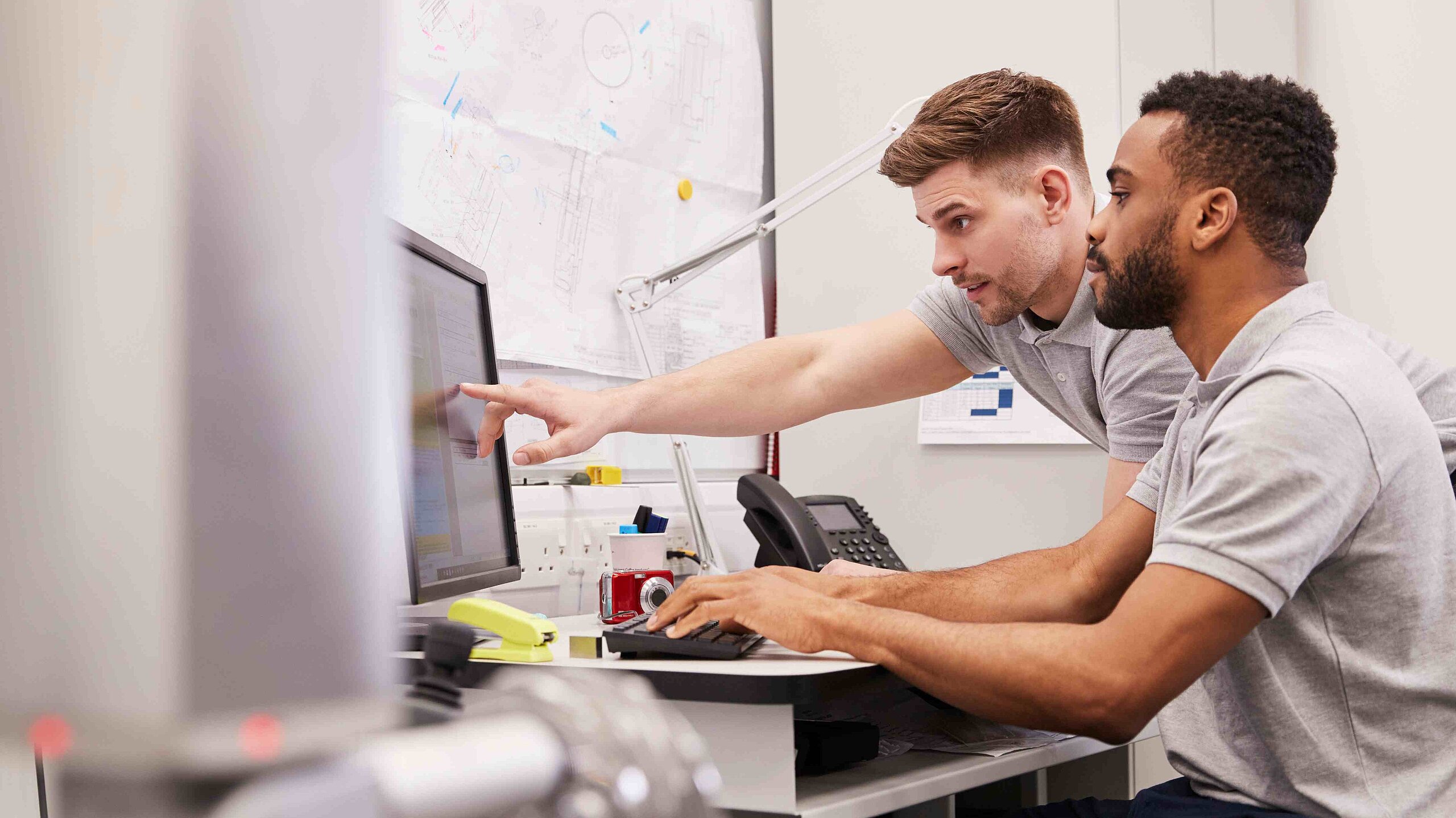 Ingenieure besprechen sich und schauen auf Computer.